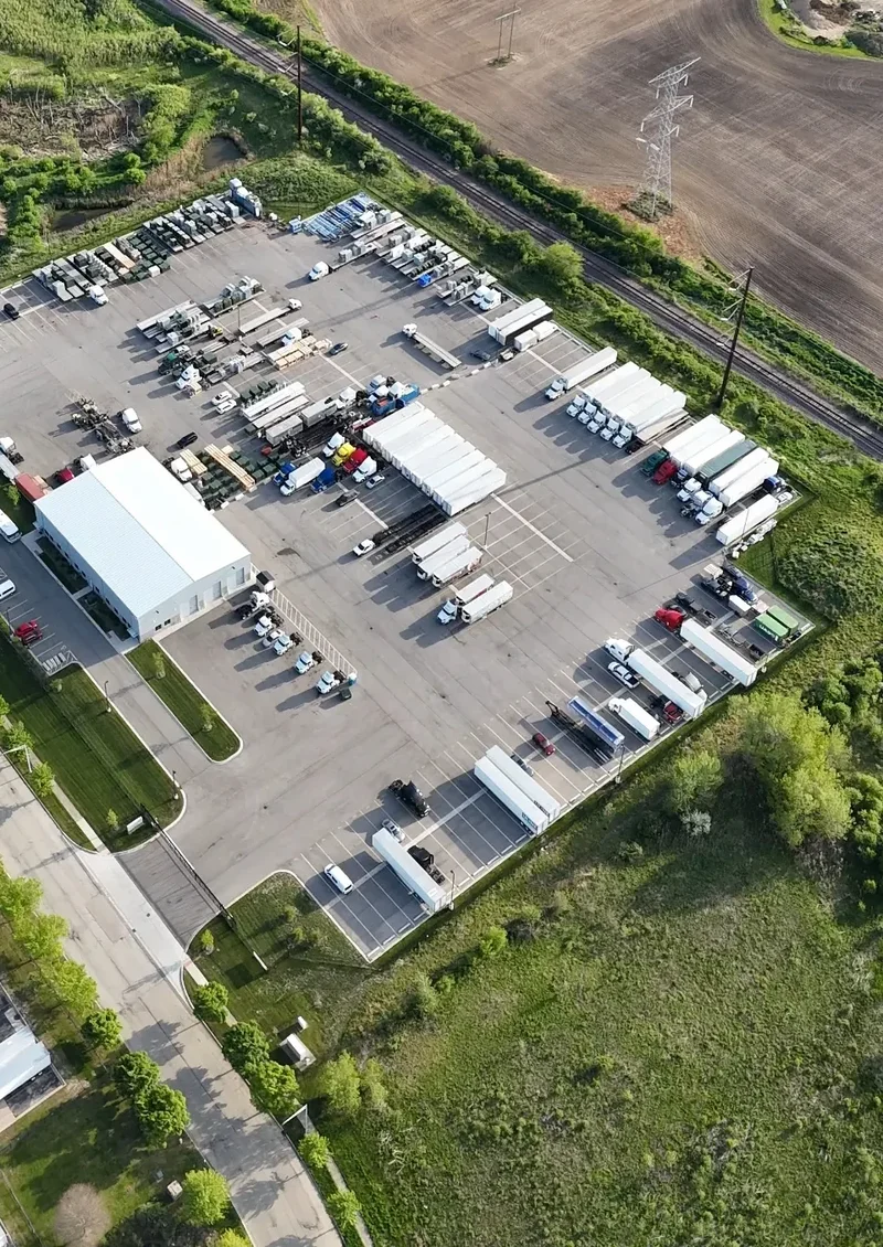 Aerial daytime view of the paved, fenced Zion Truck Parking yard with rows of parked trucks and trailers