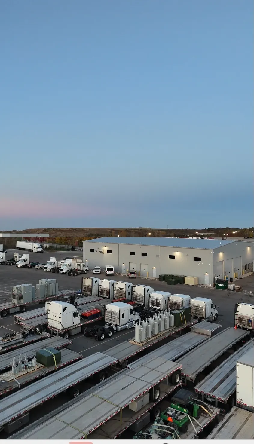 Repair shop building exterior at Zion Truck Parking, viewed from the yard at dusk with lights on