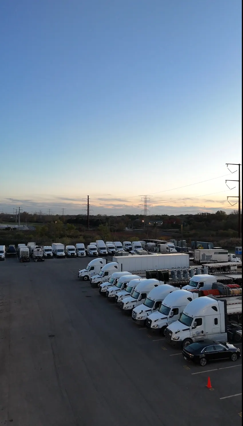 A long row of tractors parked at Zion Truck Parking at sunset